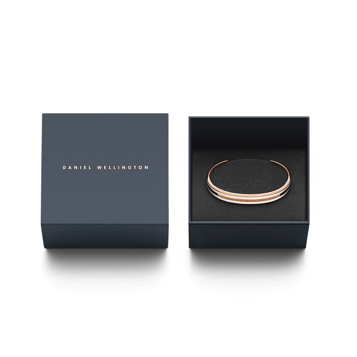 Daniel WellingtonのEmalie Slim Bracelet ローズゴールドが、ネイビーのギフトボックスに収められています。箔押しされたブランドロゴの蓋と、黒いクッションケースに丁寧にセットされたブレスレットは、贈り物にぴったりの上品な仕上がりです。