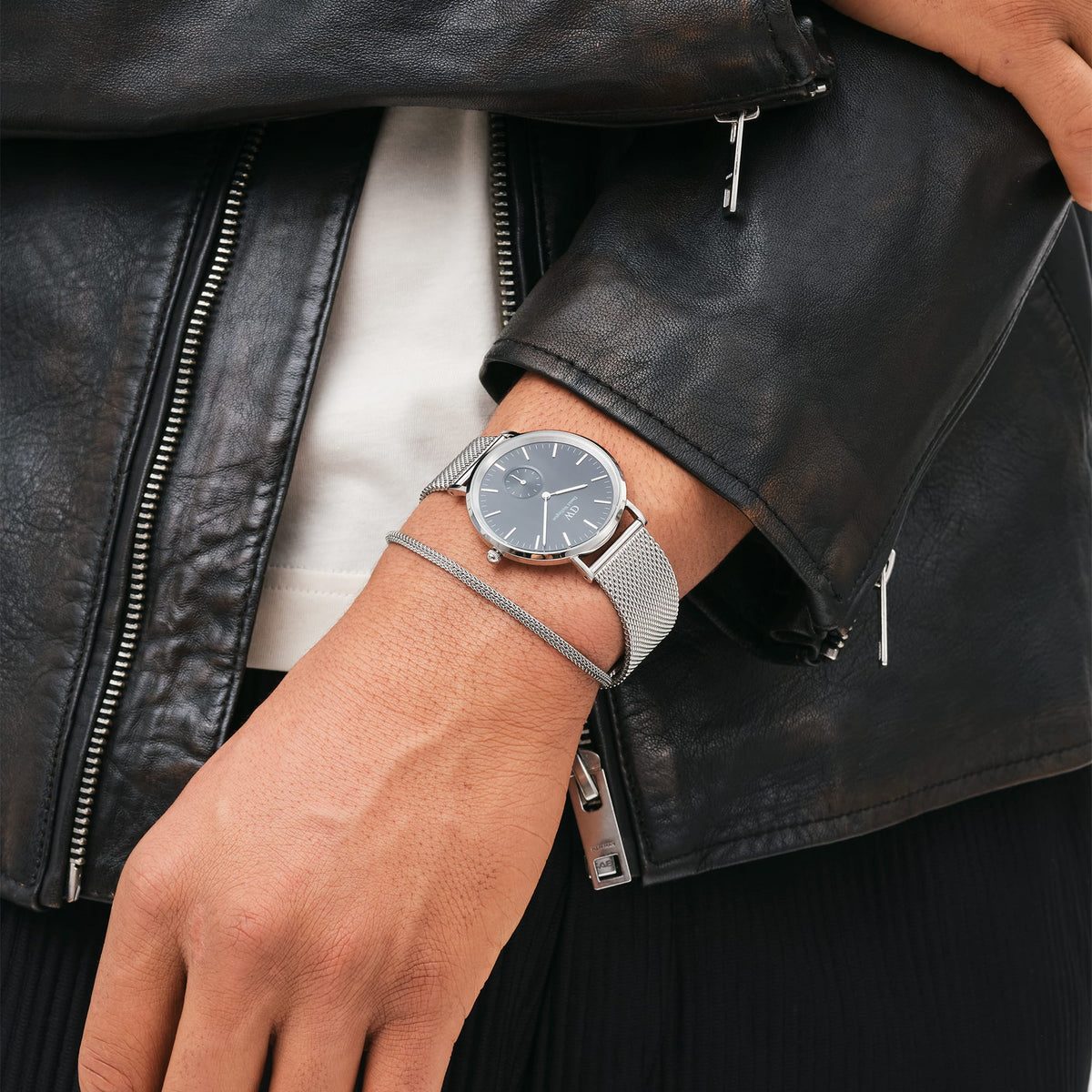 Classic Multi-Eye Sterling Onyxを着用したスタイリング例です。ブラックのレザージャケットの袖口から覗くシルバーメッシュのストラップと、オニキスブラックのダイヤルが、カジュアルな装いに洗練されたアクセントを添えています。