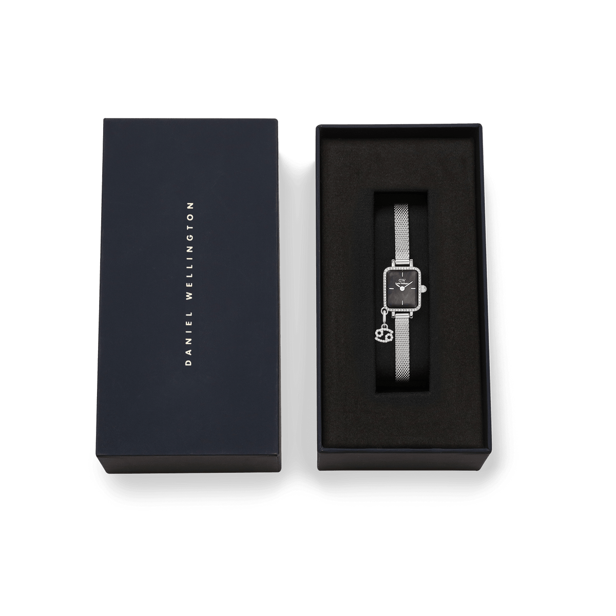 Daniel Wellingtonのネイビーのブランドボックスに収められたQuadro Mini Crystal Zodiac Sterlingです。ブラックのクッション上にシルバーメッシュストラップの時計が丁寧にセットされ、蟹座のゾディアックチャームが添えられています。ギフトにもぴったりの上品な仕上がりです。