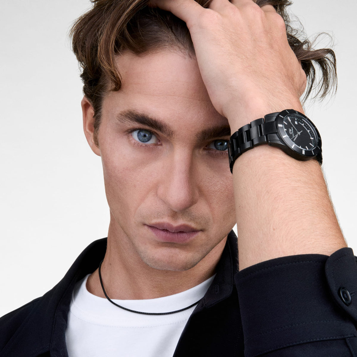 Daniel WellingtonのIconic Paradigma Link Blackを着用した男性モデル。ブラックのジャケットに、オールブラックの3リンクブレスレットが自然になじみ、手首元に上品なアクセントを添えています。