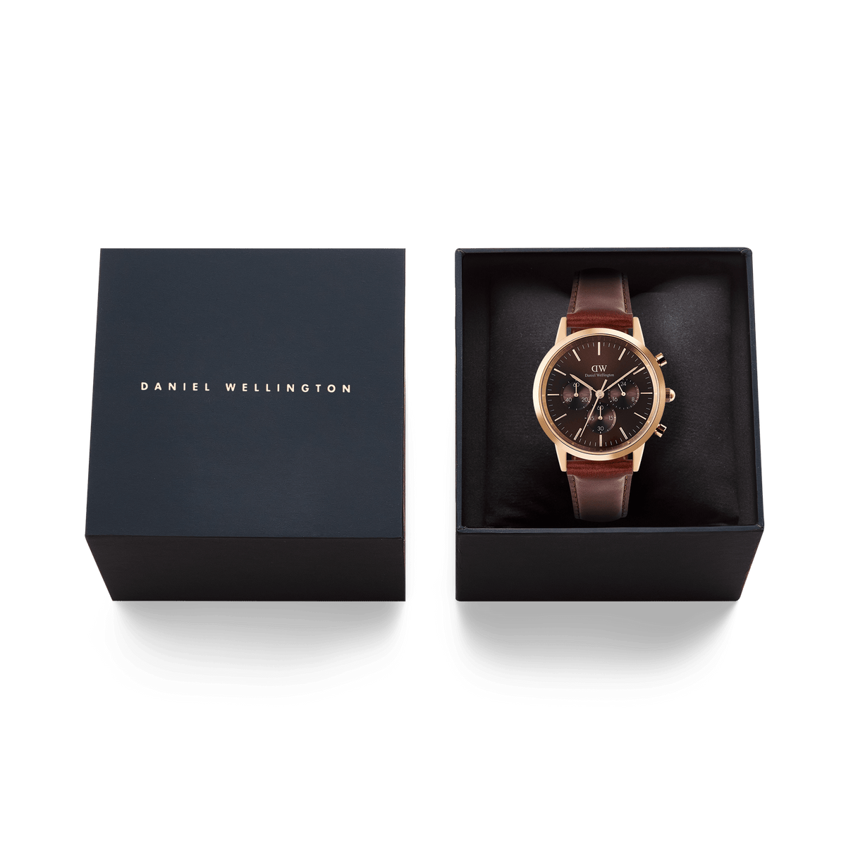 Daniel Wellington Iconic Chronograph St Mawes。ネイビーのギフトボックスに収められ、箔押しのブランドロゴが施された蓋と、クッション上にセットされたローズゴールドケース×ブラウンレザーストラップの本体が並びます。贈り物にぴったりの上品なパッケージです。