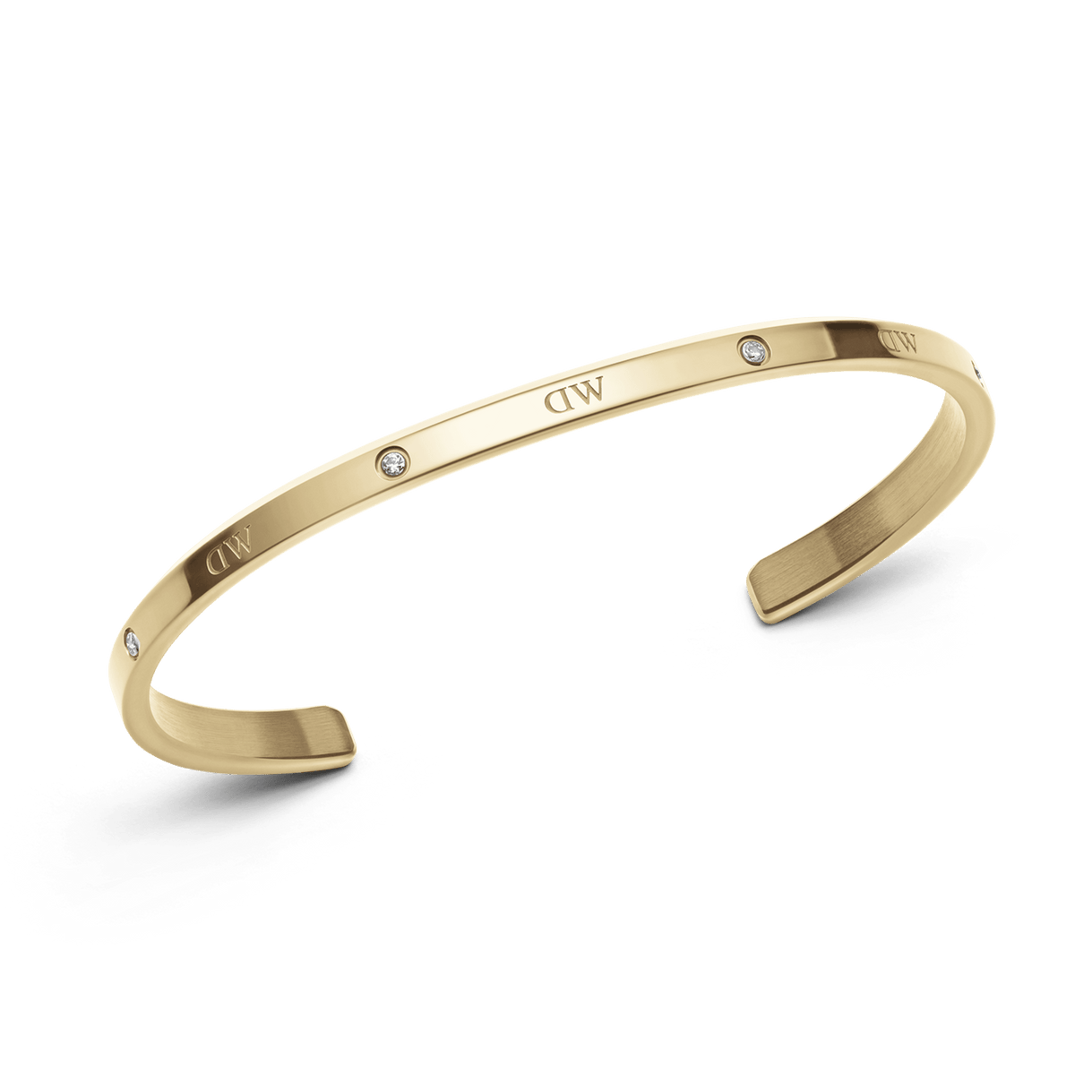 クラシックなLumine Braceletゴールドを斜めから撮影した製品写真です。ベゼルセッティングのクリスタルとブランドロゴが交互に並ぶポリッシュ仕上げの表面と、サテン仕上げの内側の質感の違いがわかるオープンカフデザインとなっています。