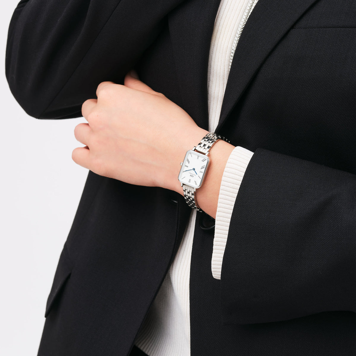 ダークジャケットにQuadro Roman Numerals 5-Link Silverを合わせたコーディネート例です。シルバーの5連ブレスレットとレクタンギュラーケースが、きれいめスタイルの手元に上品なアクセントを加えています。