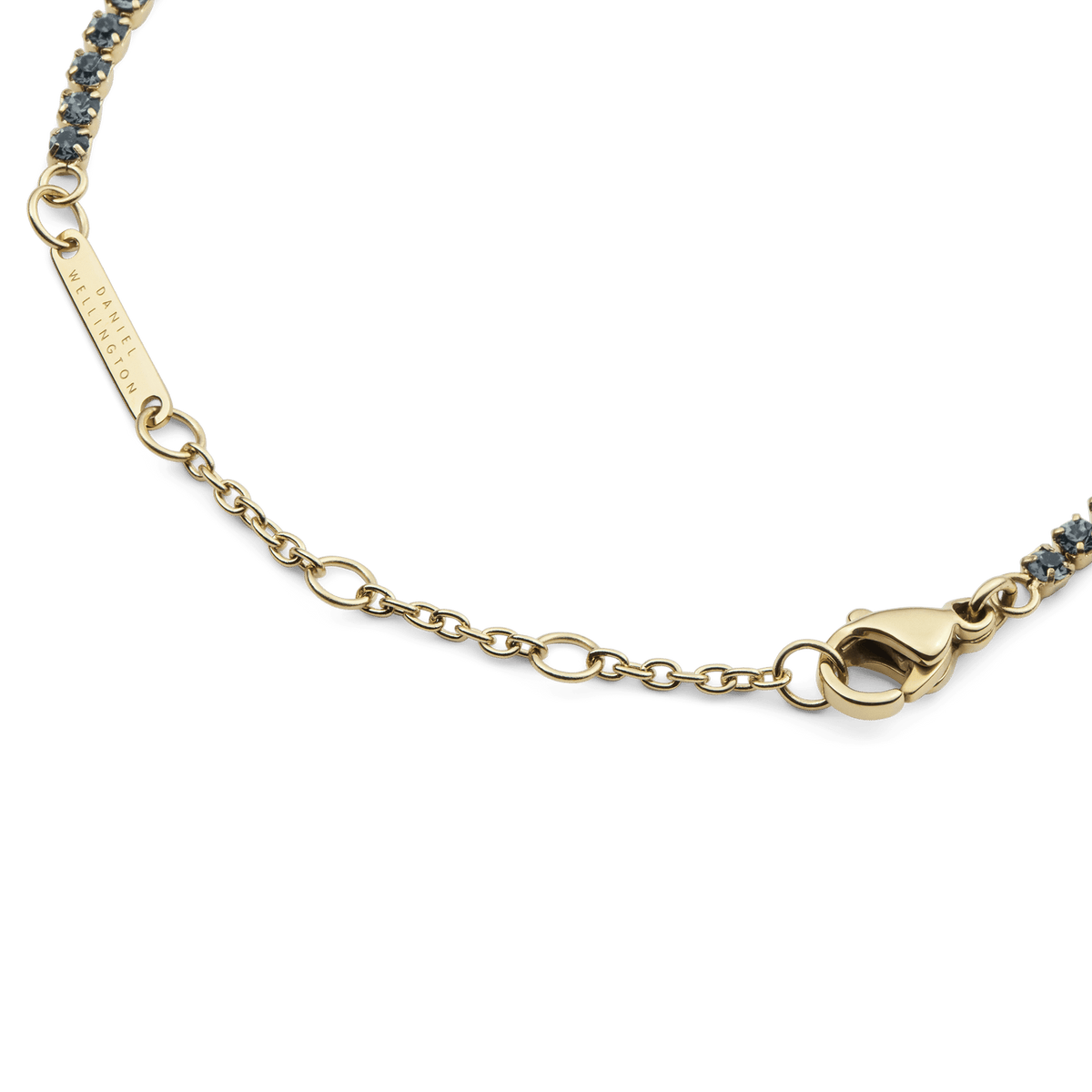 Classic Tennis Bracelet Nightfall Goldの留め具周りのディテールです。Daniel Wellingtonの刻印が施されたゴールドのブランドプレート、サイズ調整用のチェーン、ロブスタークラスプが確認できます。また、両端にはダークトーンのクリスタルがあしらわれています。
