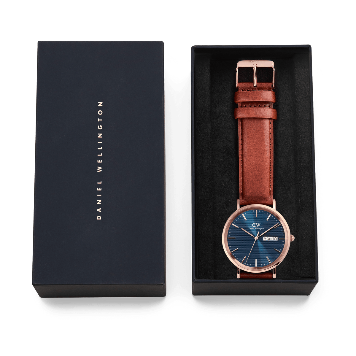 Classic Day Display St Mawes Rose Gold Arcticをネイビーのギフトボックスに収めた様子です。ブルーの文字盤とブラウンのレザーストラップが黒いクッションの上に丁寧に配置され、贈り物にぴったりの上品なパッケージングとなっています。