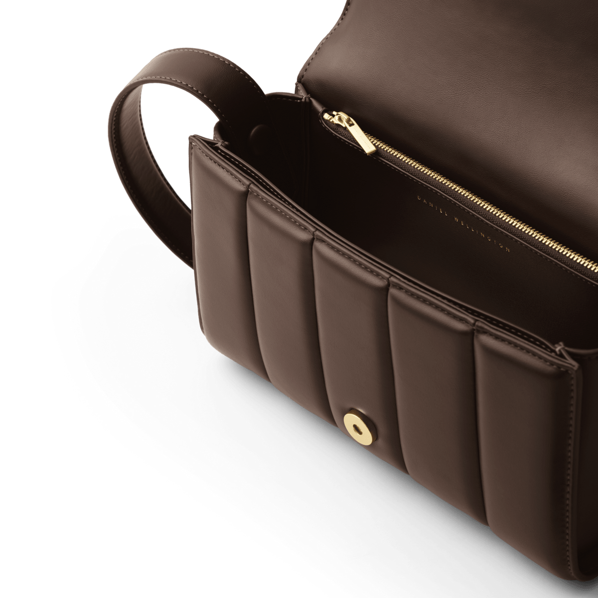 Daniel WellingtonのSadie Bag Brownのフラップを開いた内部をクローズアップした画像です。ゴールドファスナー付きの内ポケットやマグネット式のフラップ留め具、そして立体感のある縦パフキルティングのディテールが確認できます。