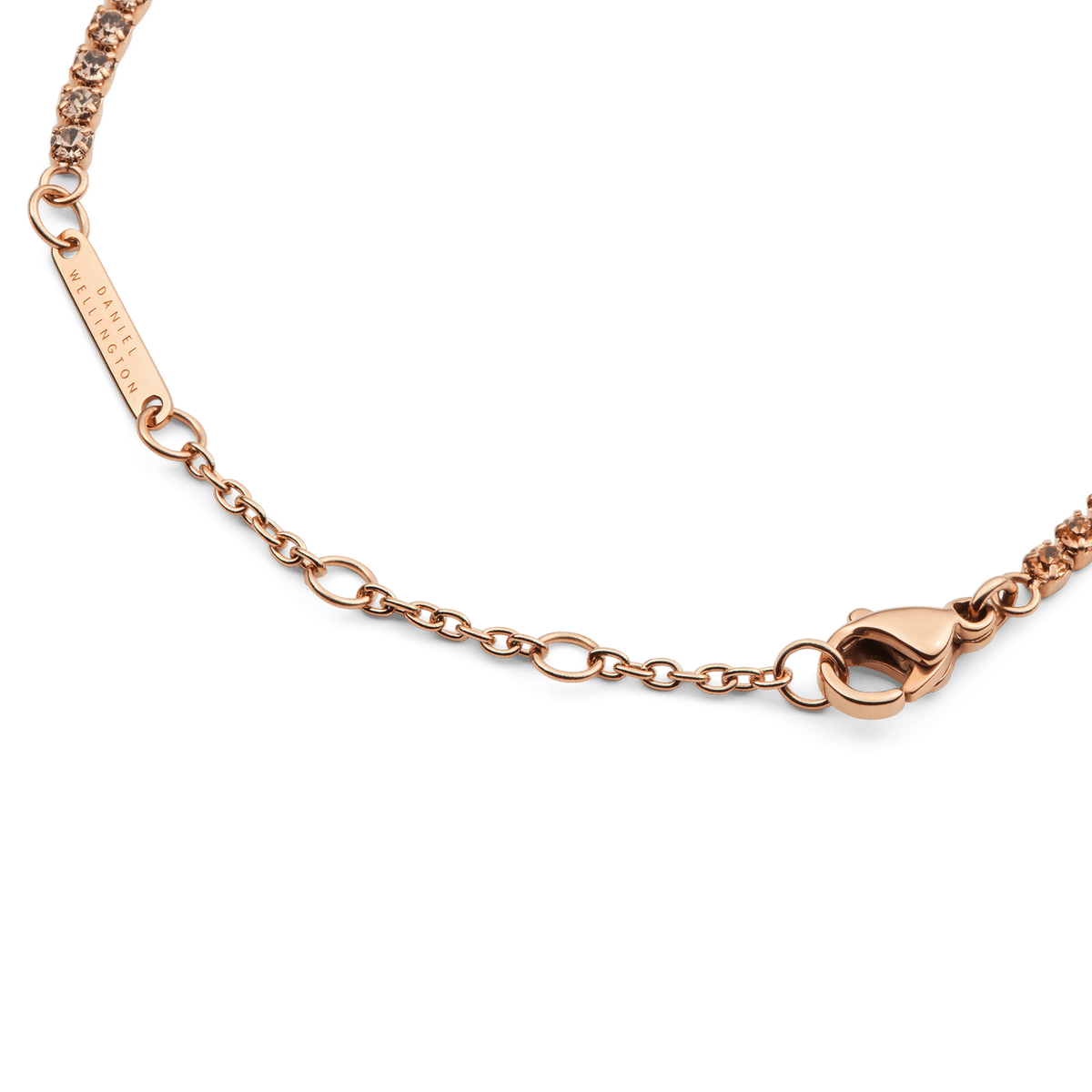 アプリコットローズゴールドのClassic Tennis Braceletのクラスプ部分をご紹介します。ローズゴールドのロブスタークラスプとサイズ調節用チェーン、Daniel Wellingtonの刻印が入ったプレートが確認でき、クリスタル部分との自然なつながりが美しい仕上がりです。