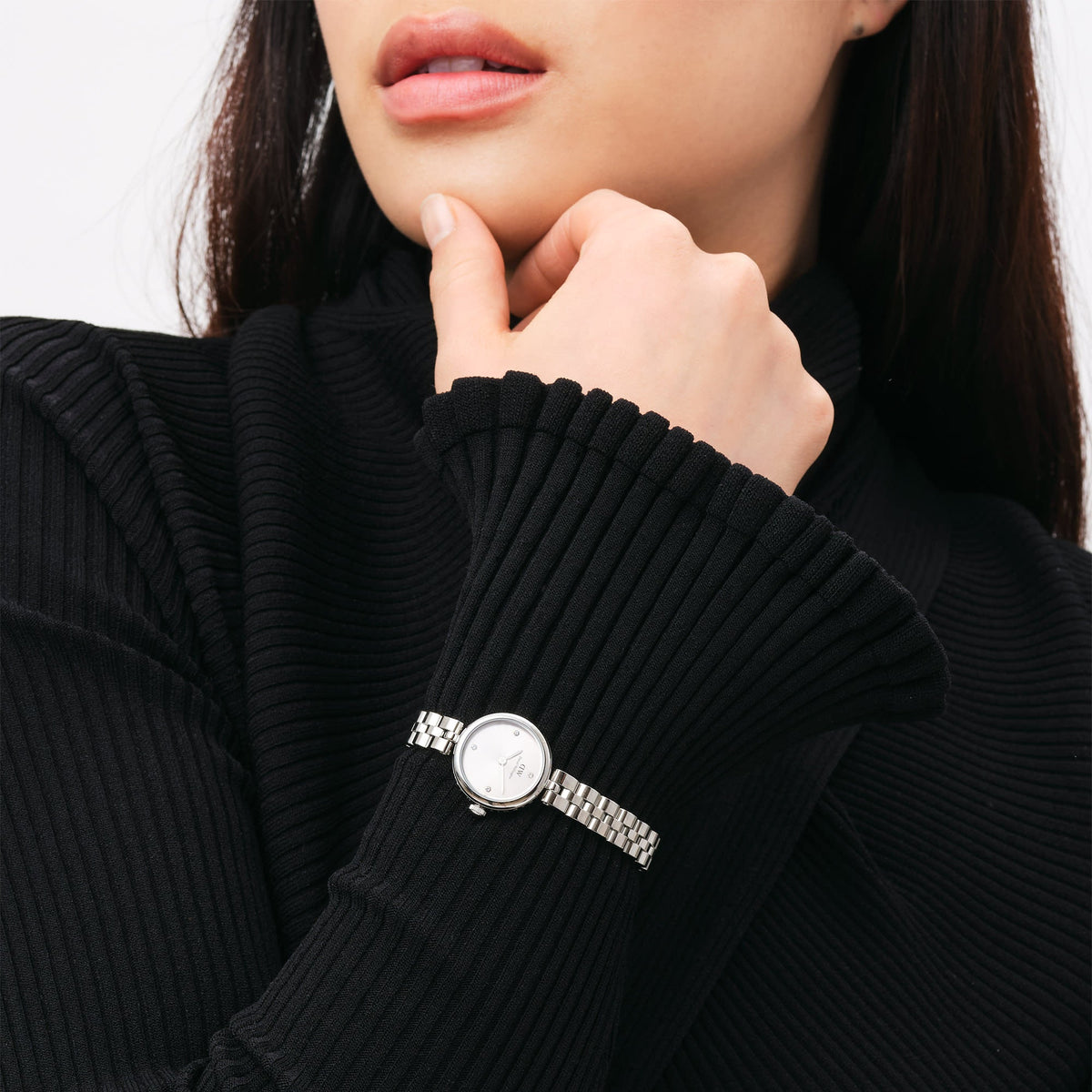 ブラックのタートルネックニットに合わせたElan Lumine Unitone Silverの着用イメージです。シルバートーンで統一されたコンパクトなケースと3連ブレスレットが、ダークな装いの手元に上品な輝きを添えます。