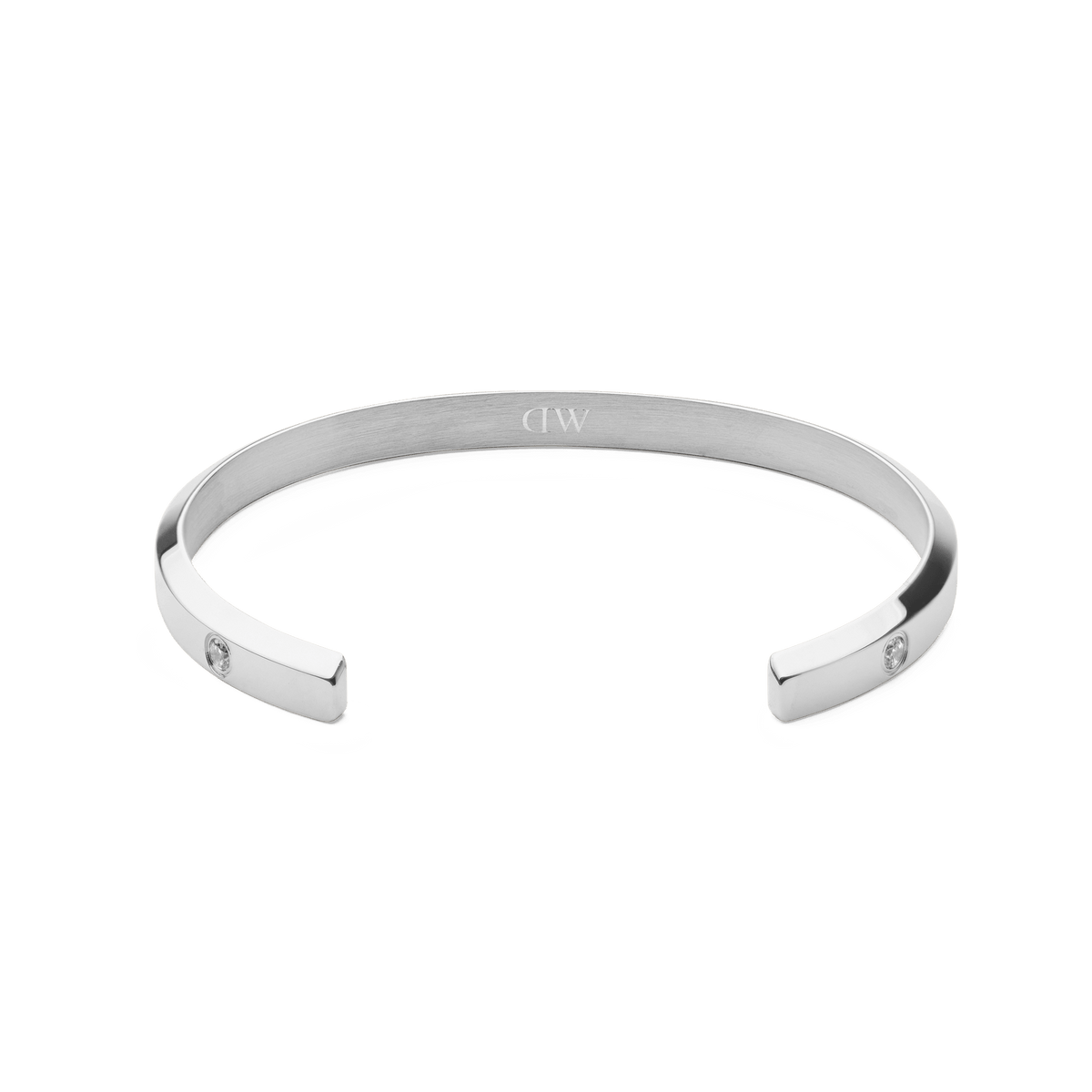 Classic Lumine Braceletシルバーの内側を正面から捉えた画像です。ヘアライン仕上げの内面中央にはDaniel Wellingtonのロゴが刻印され、両端にキュービックジルコニアがあしらわれたオープンカフデザインが特徴です。