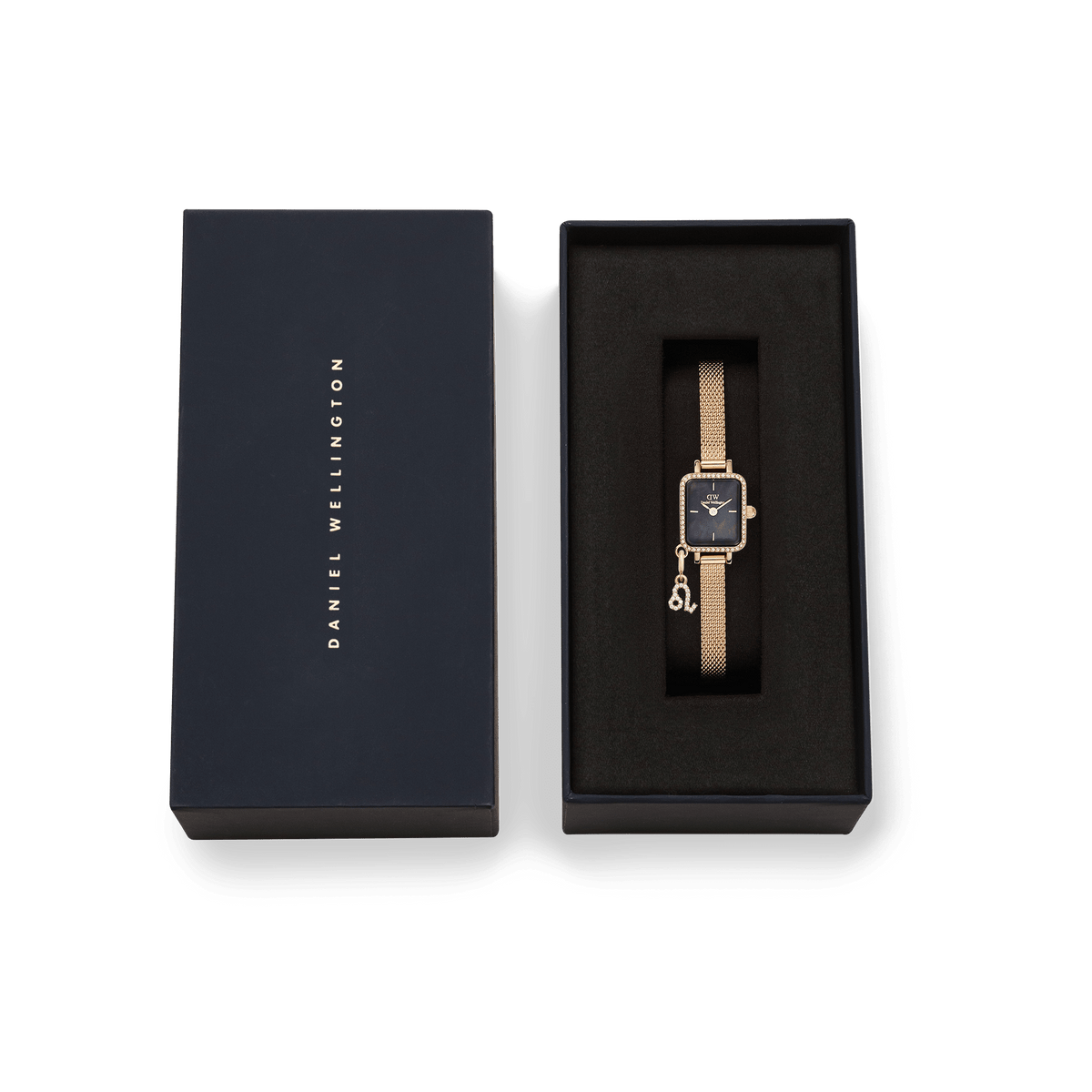 Quadro Mini Crystal Zodiac Evergoldがダークネイビーのブランドボックスに収められたギフトセットの画像です。ブラックのクッショニングにゴールドメッシュストラップの腕時計が丁寧にセットされ、ケースに付いた星座チャームも添えられています。箱の蓋にはDaniel Wellingtonのロゴが箔押しされており、贈り物にぴったりの上質な仕上がりです。