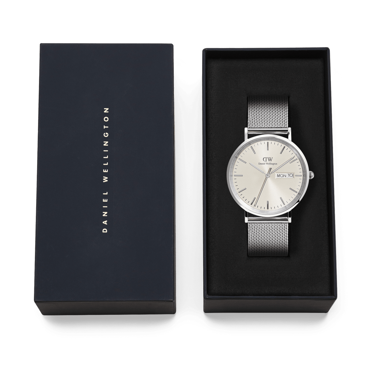ダニエルウェリントンのClassic Day Display Sterling Champagneは、ネイビーカラーのギフトボックスに収められています。シャンパンカラーの文字盤とシルバーメッシュのストラップが黒いクッションカバーの上で美しく映え、贈り物にぴったりの上品な仕上がりです。