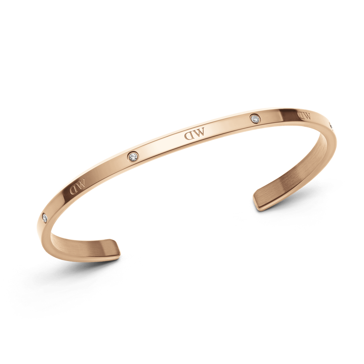 Classic Lumine Braceletのローズゴールドカフを斜めから捉えた写真です。光を受けたポリッシュ面にクリスタルが輝き、オープンカフの開口部やサテン仕上げの内側のディテールが確認できます。
