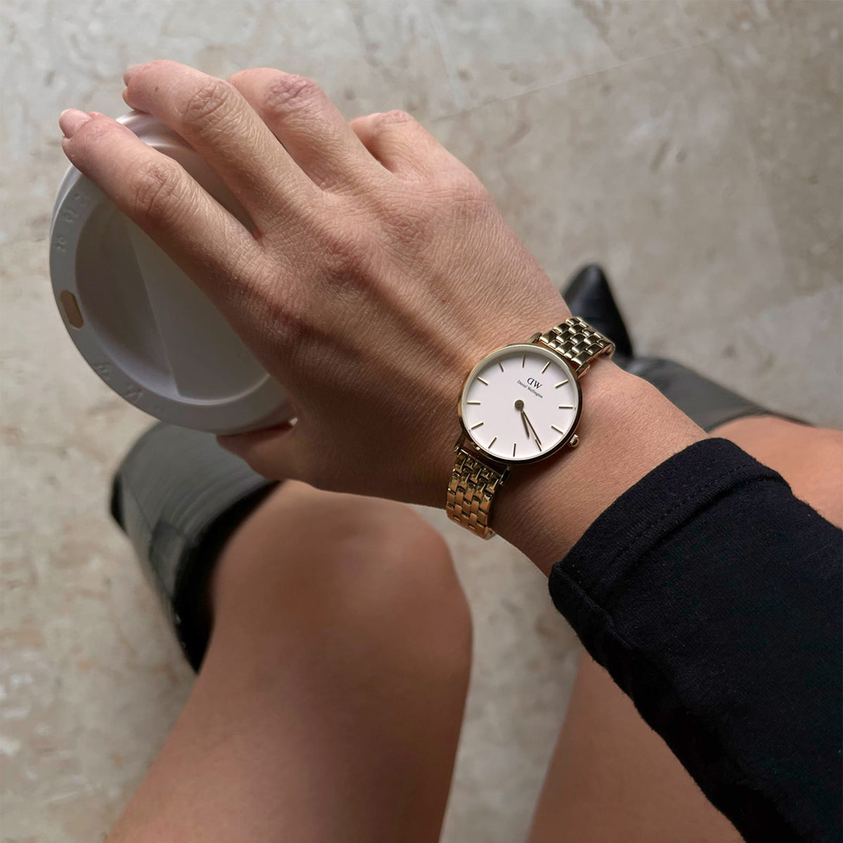 Petite 5-Link Evergoldを手首に着けた女性のライフスタイル写真です。コーヒーカップを手にした日常のひとコマで、ゴールドの5連リンクブレスレットが手元に自然になじんでいます。