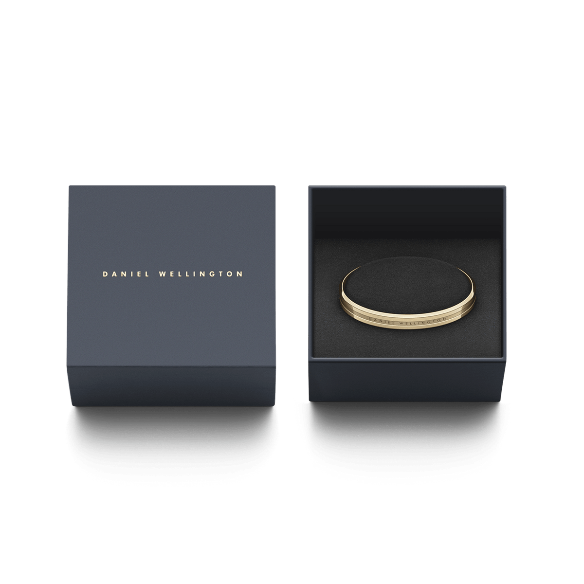 Daniel Wellington Elan Braceletのゴールドカフブレスレットが、ネイビーのブランド専用ギフトボックスに収められています。ブラックのクッション上にブレスレットが丁寧にセットされ、贈り物にふさわしい上品な仕上がりです。