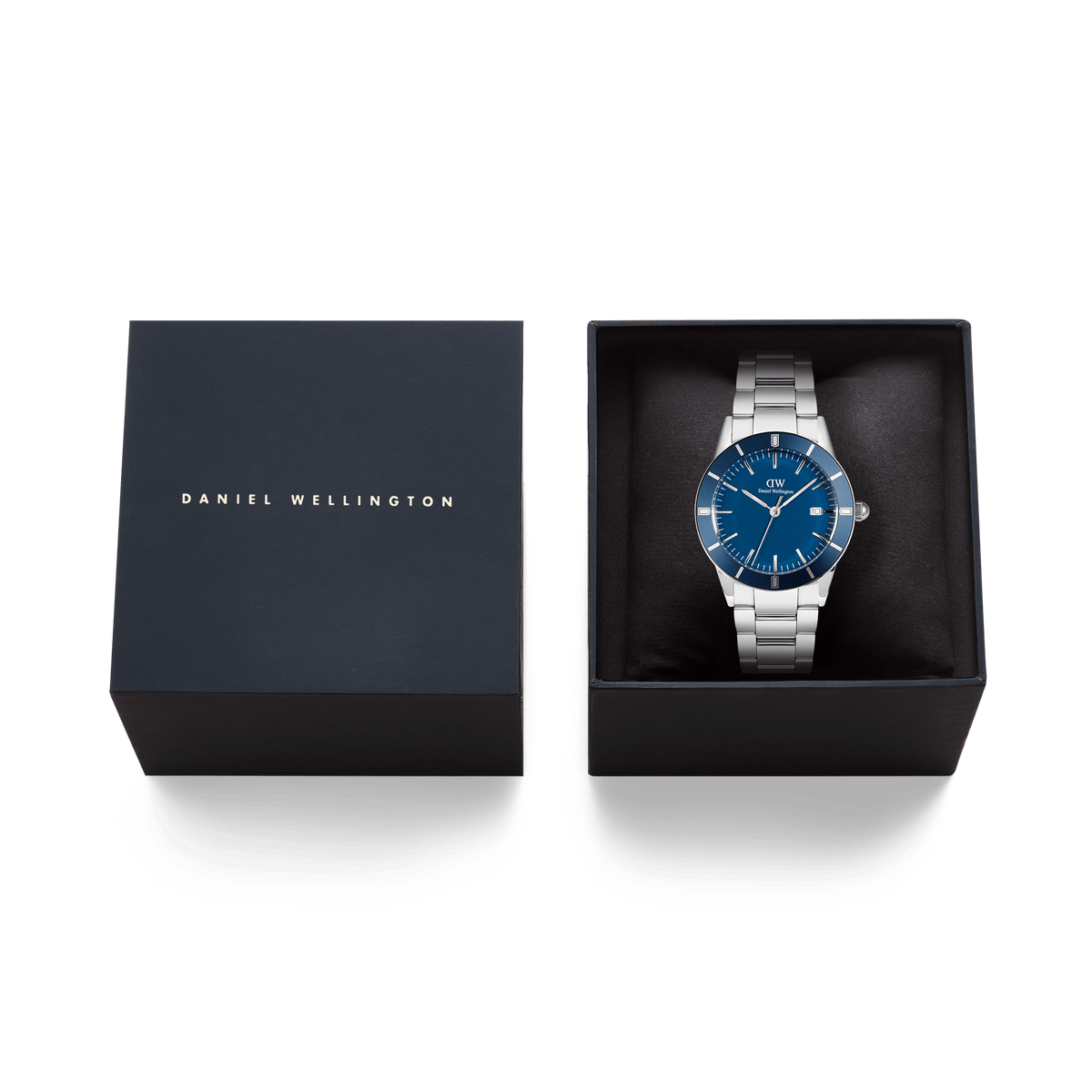 アイコニックなParadigma Link Blue Enamel Silverが、ダークネイビーのブランドロゴ入りギフトボックスに収められています。ブルーエナメルの文字盤とシルバーブレスレットが黒いクッションカバーの上で美しく映え、贈り物にぴったりの上質なパッケージです。