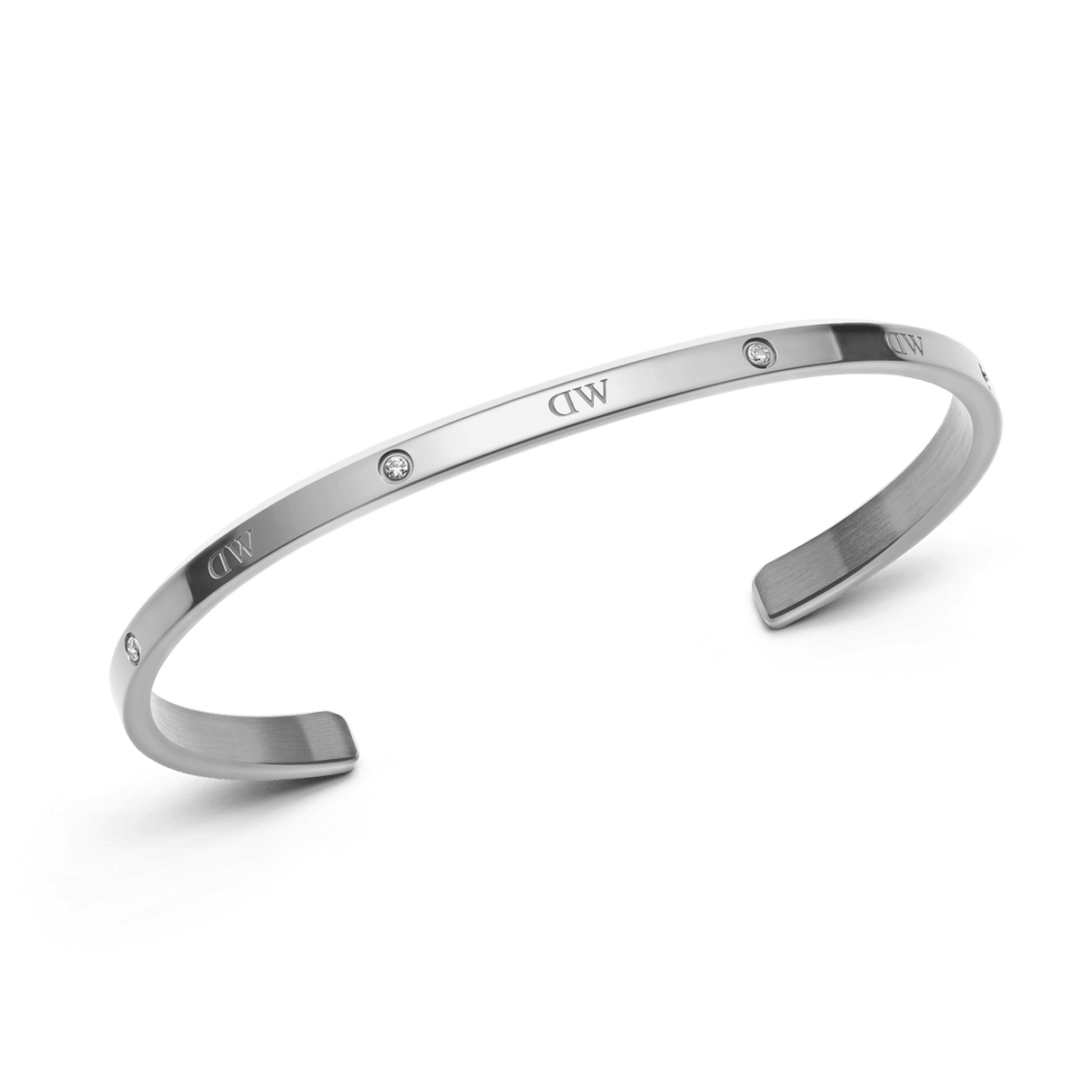 Daniel Wellington Classic Lumine Bracelet Sを斜めから捉えた商品画像です。シルバーカラーのオープンカフの立体的なフォルムや、表面に刻印されたロゴ、クリスタルの配置、端部のマット仕上げなどが確認できます。