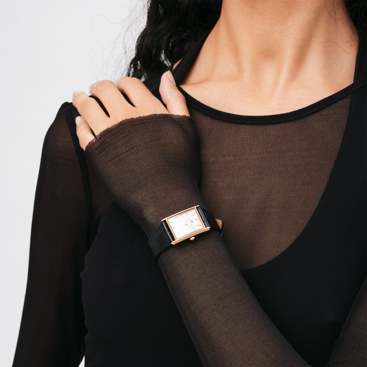 ブラックのトップスを着た女性が、Daniel WellingtonのBound Black Crocodile Rose Goldを手首に着用している様子です。長方形のローズゴールドケースとブラックレザーストラップが、シックな装いに自然になじんでいます。
