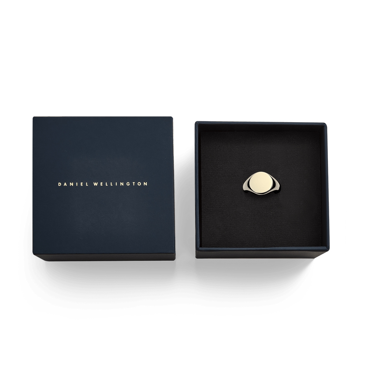 ダニエルウェリントン Classic Signet Ring Goldが、ネイビーの専用ギフトボックスに収められた状態です。ブラックのクッショニングの上にゴールドのシグネットリングが置かれ、蓋にはゴールドのブランドロゴが箔押しされています。贈り物にぴったりの上品なパッケージです。