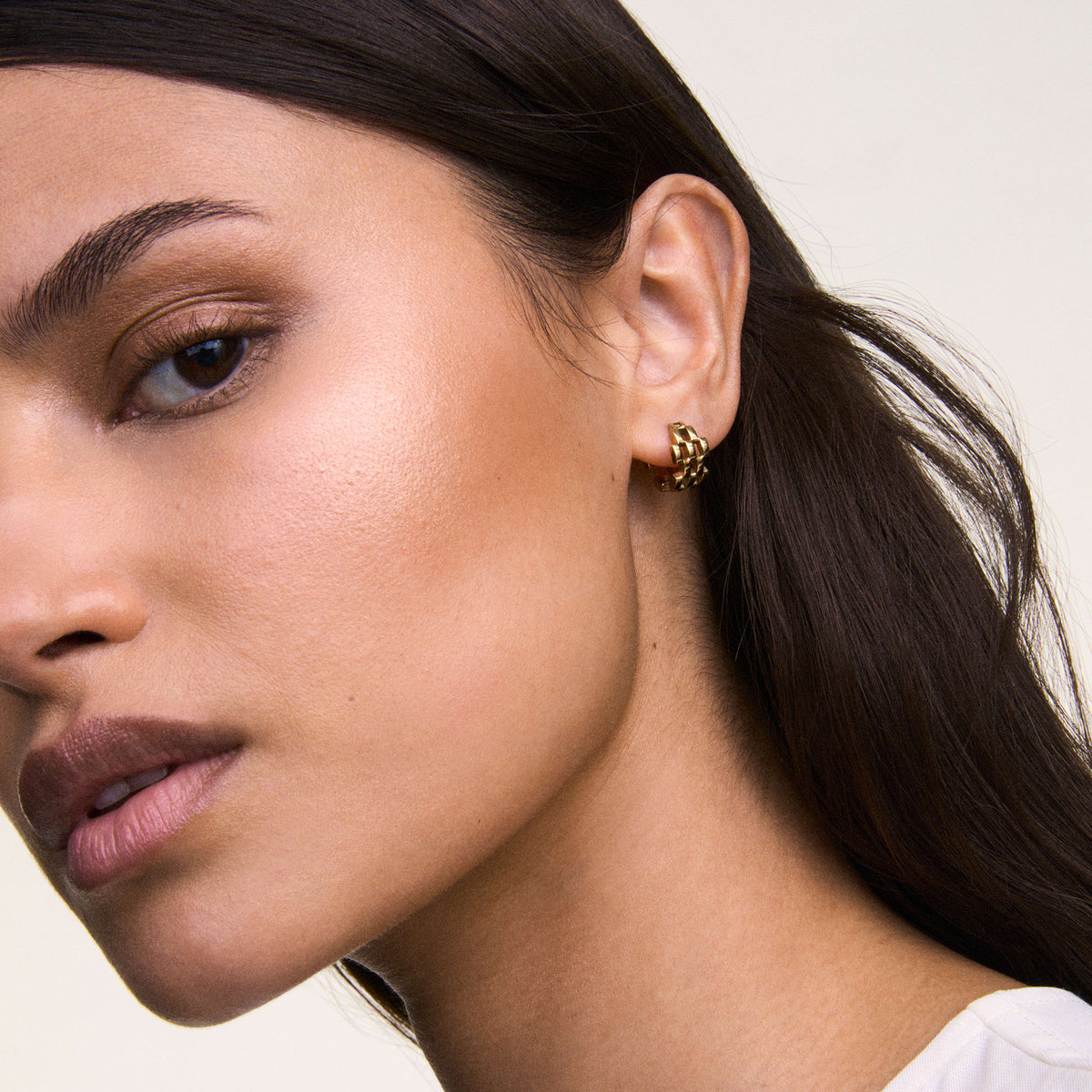 ダニエルウェリントンの5-Link Earrings Goldを着用したモデルのクローズアップ写真。5連リンクのコンパクトなゴールドフープピアスが耳元で光を受け、ナチュラルメイクとホワイトトップスに上品に映えます。