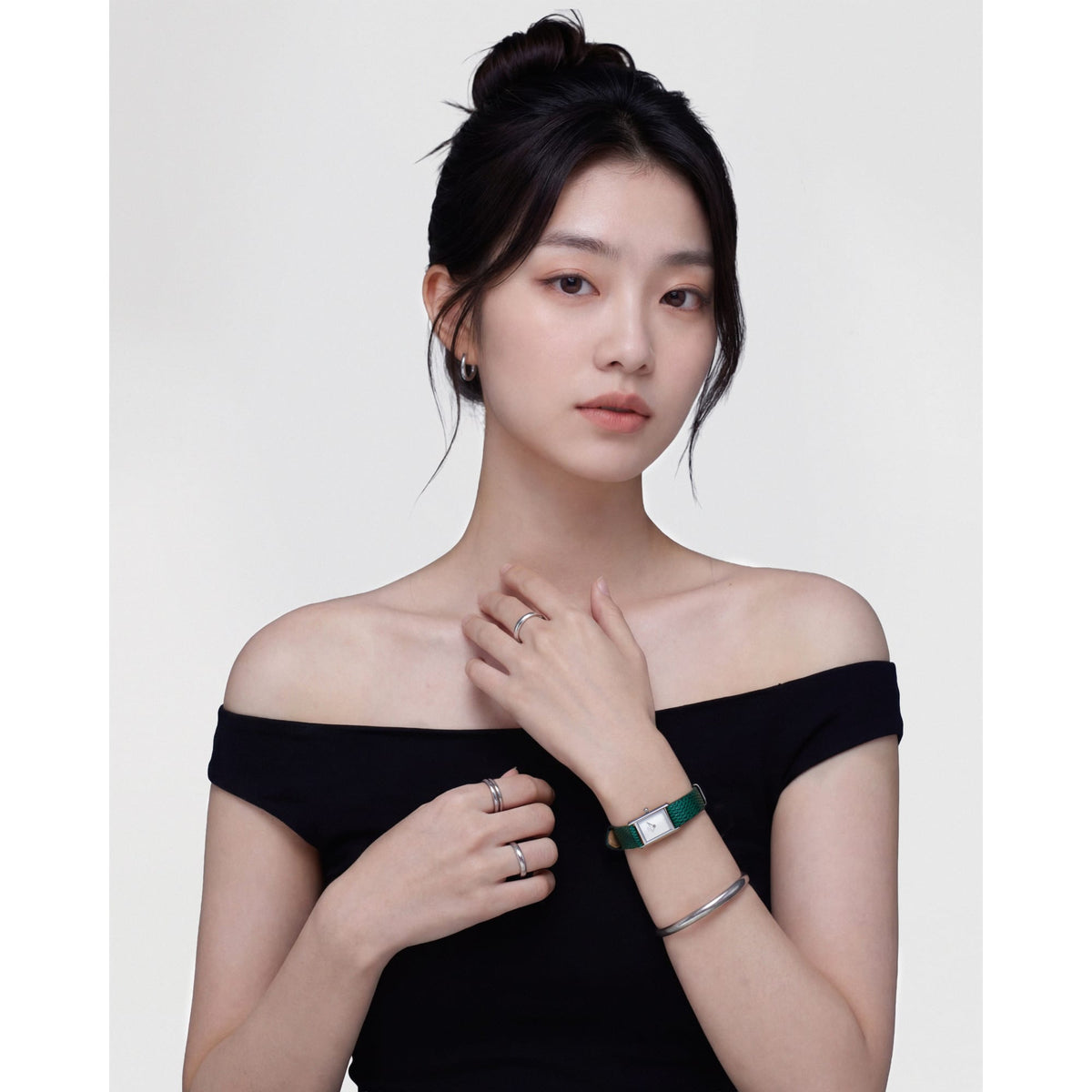 Daniel Wellington Arch Earrings Silverを耳元に合わせたスタイリングイメージ。黒のオフショルダートップスにシルバーフープピアスやリング、バングルをコーディネートし、控えめながらも統一感のある着こなしを演出しています。