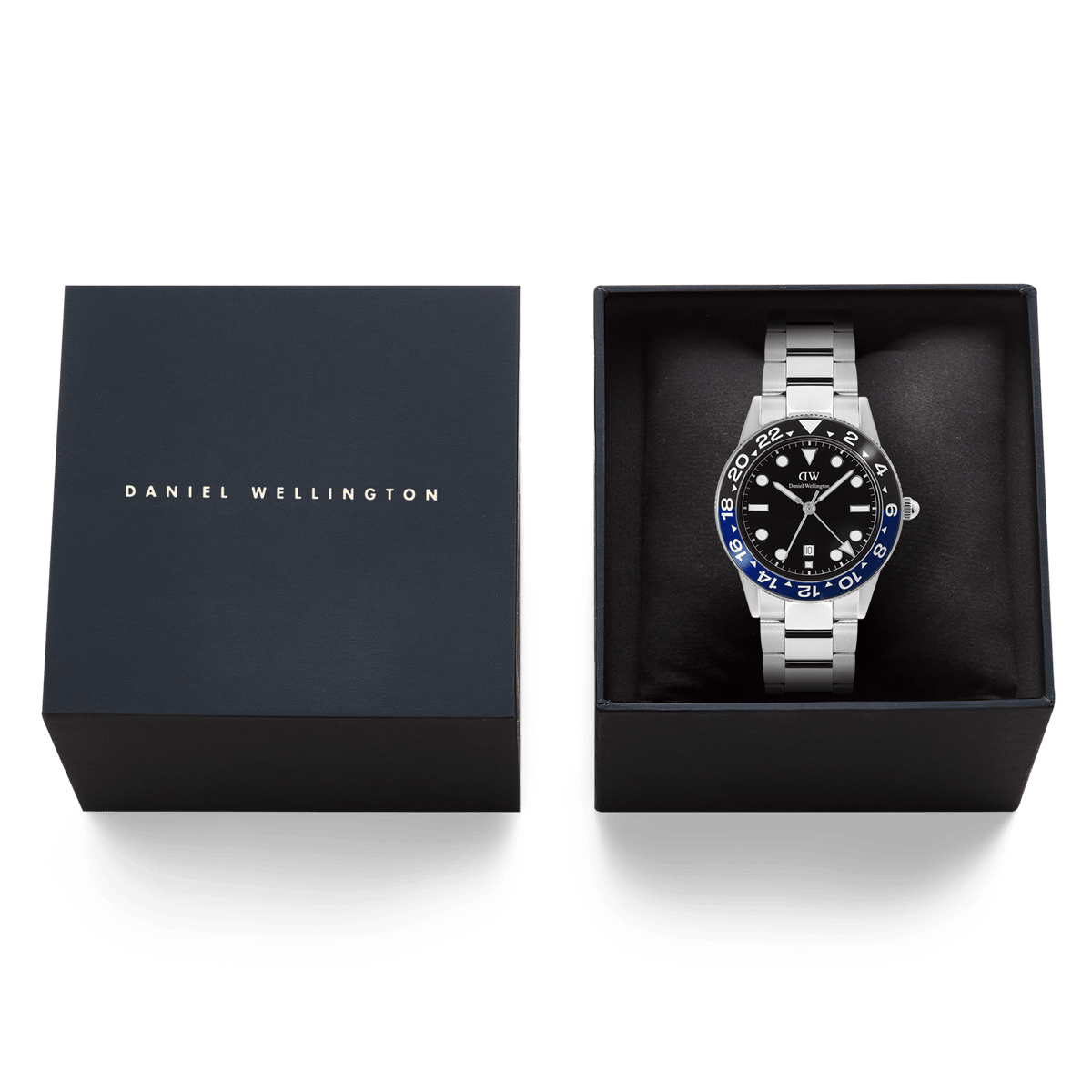 ダニエルウェリントン Iconic GMT Link Black Blue Ceramic Bezel Silverが、ネイビーのブランドロゴ入りギフトボックスに収められています。ブラックのクッションの上にシルバーリンクブレスレットの腕時計が丁寧にセットされており、贈り物に最適な上質なパッケージです。