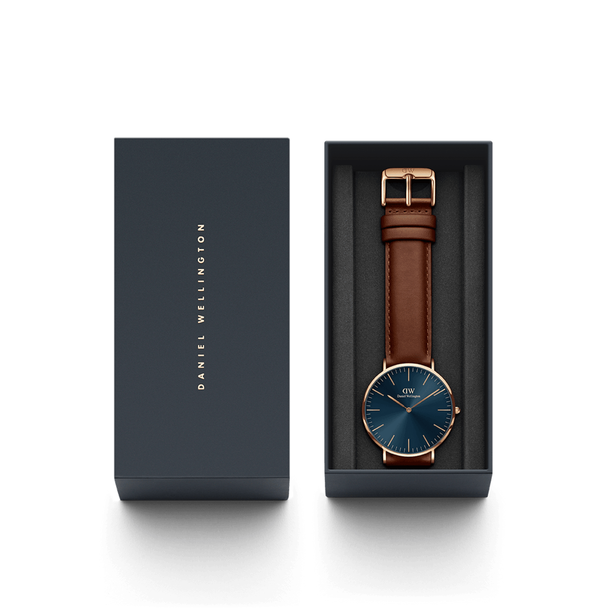 クラシック St Mawes Arctic Rose Goldが、ネイビーの専用ギフトボックスに収められた様子です。ブルーのサンレイダイヤルとブラウンのレザーストラップが黒いクッションの上に整えられ、贈り物にぴったりの上品なパッケージに仕上がっています。