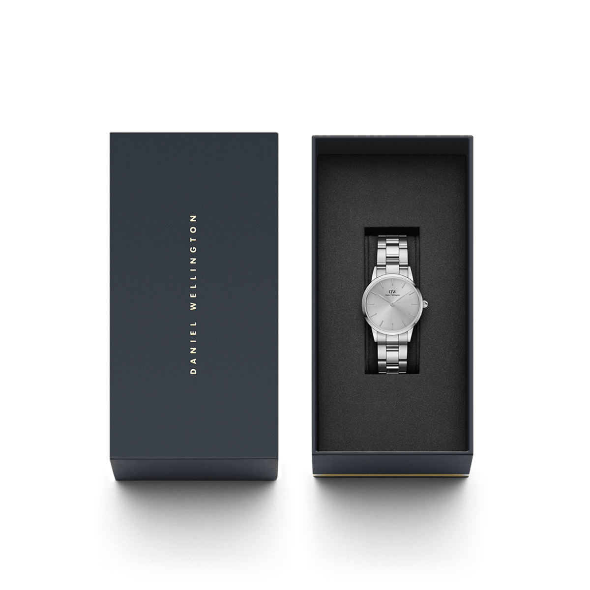 Iconic Link Unitone Silverがダークネイビーのギフトボックスに収められたパッケージ画像です。箱の蓋にはDaniel Wellingtonのロゴが箔押しされ、ブラックのクッショニング内装にシルバーの腕時計が丁寧にセットされています。贈り物に最適な上品な仕上がりです。