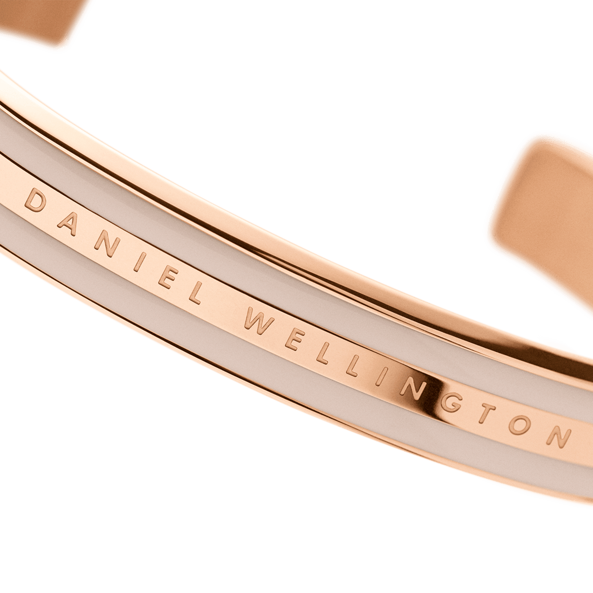 Emalie Bracelet Desert Sand Rose Goldのロゴ部分をマクロ撮影した画像です。ローズゴールドのポリッシュ仕上げフレームに刻まれたDaniel Wellingtonの文字と、隣接するデザートサンドカラーのエナメル面の滑らかな質感が鮮明に捉えられています。