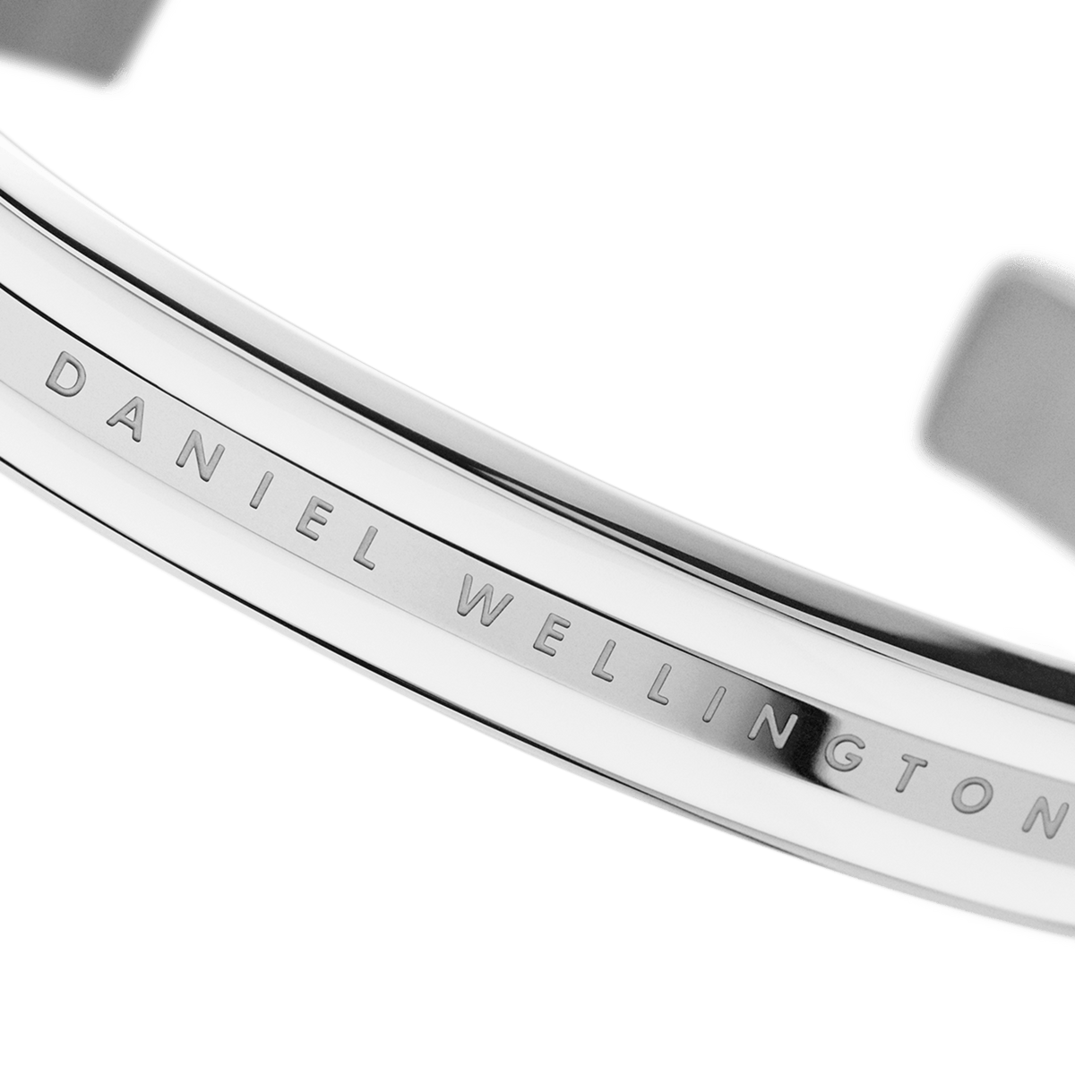 Emalie Braceletのシルバーのロゴ刻印部分を斜めから捉えたディテール画像です。ポリッシュ加工のステンレススチール表面に光が反射し、滑らかな質感とDaniel Wellingtonの繊細なレタリングが際立っています。
