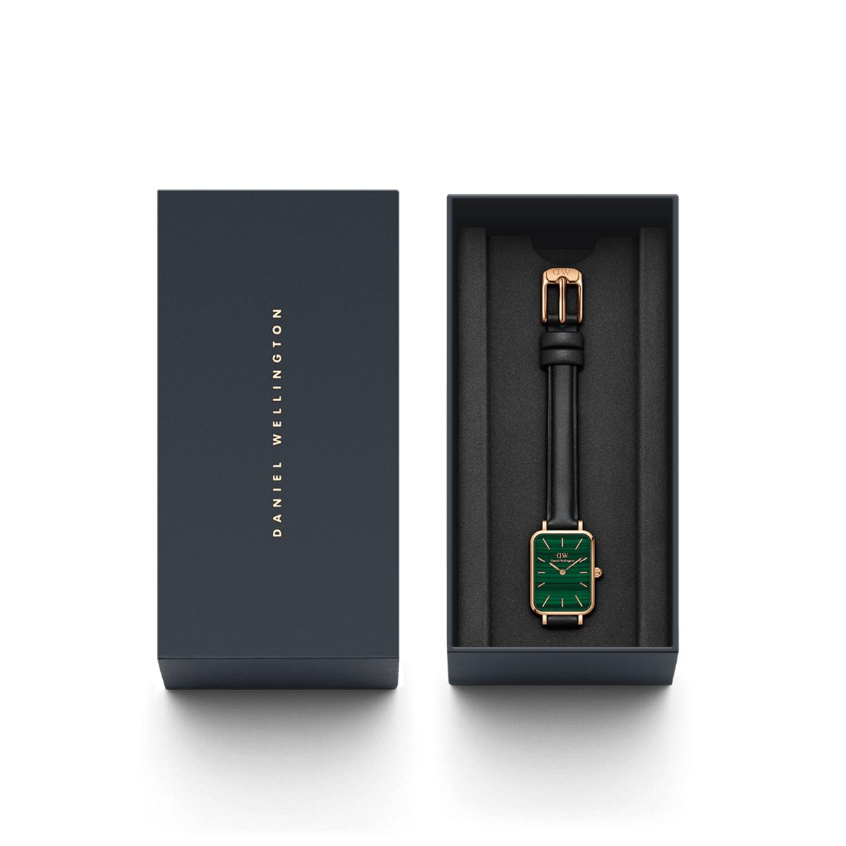 Quadro Pressed Sheffield Green Rose Goldがダークネイビーの専用ギフトボックスに収められた様子です。箱の蓋にはDaniel Wellingtonのロゴが箔押しされ、グリーンの文字盤とブラックレザーストラップの腕時計が黒いクッションに丁寧にセットされています。贈り物にぴったりの上品なパッケージです。