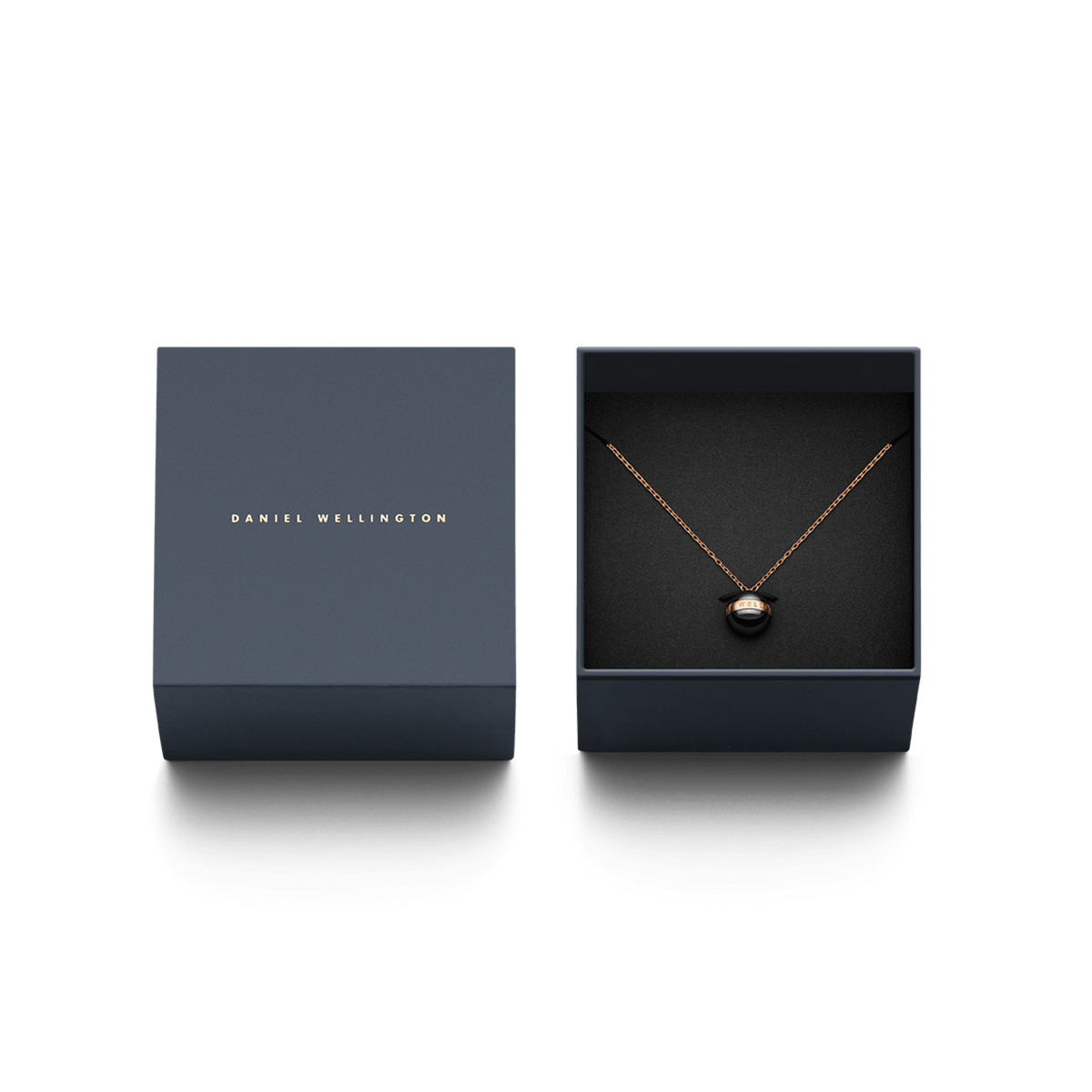 Daniel WellingtonのAspiration Necklace Rose Gold Blackは、ダークグレーのギフトボックスに収められています。ブラックセラミックの球体ペンダントとローズゴールドのチェーンが黒いクッションの上に美しく配置され、贈り物にぴったりの上品なパッケージです。