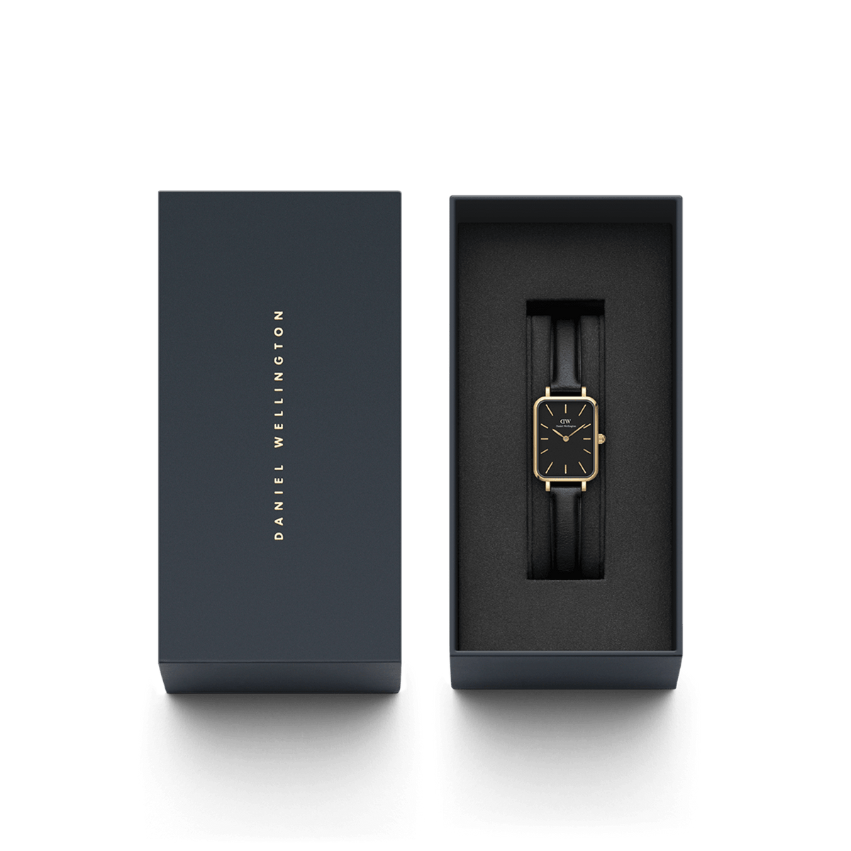 ダニエルウェリントンのブランドロゴを箔押ししたネイビーカラーのギフトボックスに収められたQuadro Pressed Sheffield Black Gold。ブラックレザーストラップとゴールドケースの腕時計が黒いクッションの上に上品に配置され、贈り物にぴったりのパッケージです。