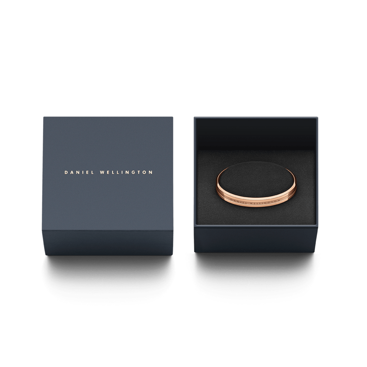 ダニエルウェリントン Elan Bracelet ローズゴールドが、ブランドロゴ入りのネイビーギフトボックスに収められています。ブラックのクッションにセットされたブレスレットは、贈り物に最適なパッケージです。