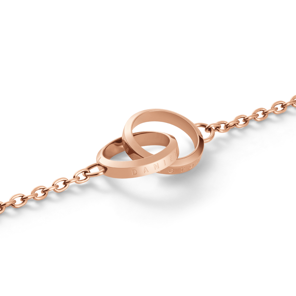Elan Unity Braceletのインターロッキングリング部分をクローズアップした画像です。ローズゴールドの輝きを放つ2つのリングが美しく交差し、Daniel Wellingtonのロゴ刻印と繊細なケーブルチェーンのディテールが際立っています。