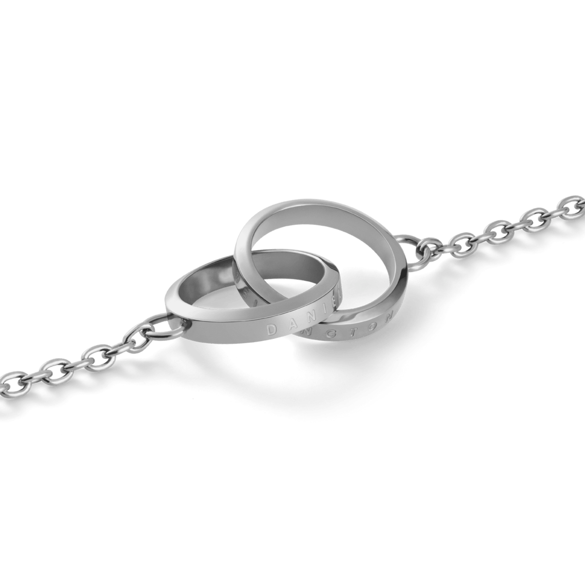 Elan Unity Necklaceのインターロッキングリング部分をクローズアップした画像です。ポリッシュ仕上げのシルバーカラーが光を反射して輝き、リングの側面にはDaniel Wellingtonのロゴがさりげなく刻印されています。