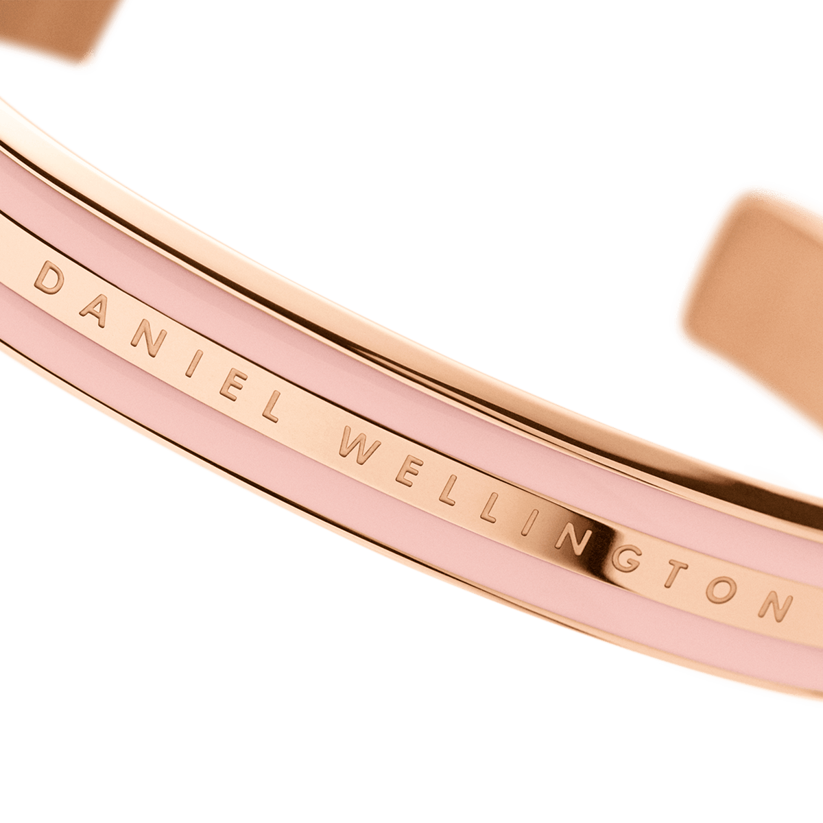 Emalie Bracelet Dusty Rose Rose Goldのロゴ刻印部分を正面から大きく捉えた接写画像です。ローズゴールドの中央バンドに刻まれたDaniel Wellingtonの文字と、両側のダスティローズエナメルの滑らかな質感が確認できます。