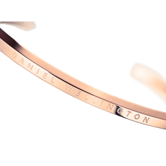 Classic Valentine Bracelet Rose Goldをマクロ撮影した正面画像。ポリッシュ仕上げのローズゴールド表面にDaniel Wellingtonのブランド名が精緻に刻印されており、細身のカフが描くなめらかなカーブと鏡面のような光沢が際立っています。