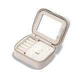 Daniel WellingtonのTravel Jewellery Box Whiteを蓋を開けた状態でご紹介します。蓋の裏側にはミラーを、内部にはリング用のロール仕切りやピアス固定用の穴付きトレイなど、多機能な収納スペースを備えています。ゴールドジッパーと上質な起毛素材の内装が特徴です。