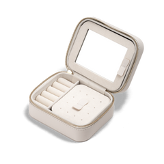 Daniel WellingtonのTravel Jewellery Box Whiteを蓋を開けた状態でご紹介します。蓋の裏側にはミラーを、内部にはリング用のロール仕切りやピアス固定用の穴付きトレイなど、多機能な収納スペースを備えています。ゴールドジッパーと上質な起毛素材の内装が特徴です。