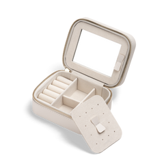 ホワイトのTravel Jewellery Boxの蓋を開け、ピアス用トレイを取り外した状態です。トレイ表面にはピアスを収納できる複数の穴が設けられており、下段にはリング用のロール仕切りや区切り付きスペースが配置されています。蓋の裏側にはミラーが取り付けられ、ゴールドのジッパーがアクセントになっています。