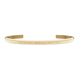 Daniel Wellington Classic Braceletのゴールドカフブレスレット正面画像。細身のオープンカフにブランドロゴが控えめに刻印された、ミニマルなデザインです。