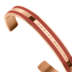 Emalie Bracelet Cherry Blush Rose Goldを斜めから捉えたディテール画像です。チェリーブラッシュのエナメルラインの間にDaniel Wellingtonの刻印が確認でき、ローズゴールドのポリッシュ仕上げが光を反射して美しく輝いています。