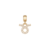 おうし座のCrystal Zodiac Charm Gold。円形と上部に広がる2本の角をあしらったタウラスのシンボルには、キュービックジルコニアが丁寧にセットされています。ゴールドのベイルとともに、白い背景で撮影した一枚です。