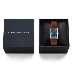 ダニエルウェリントンのギフトボックスに収められたBound Light Brown Arctic Guilloché Silverの画像です。箔押しのブランドロゴが施された蓋と、黒いクッショニングの上にセットされたアークティックブルーの文字盤を持つスクエア型腕時計が並び、贈り物にぴったりの上品なパッケージングが確認できます。