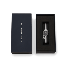 Daniel Wellingtonのネイビーのブランドボックスに収められたQuadro Mini Crystal Zodiac Sterlingです。ブラックのクッション上にシルバーメッシュストラップの時計が丁寧にセットされ、蟹座のゾディアックチャームが添えられています。ギフトにもぴったりの上品な仕上がりです。