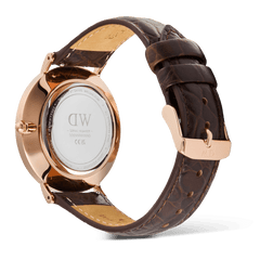 Daniel Wellington Classic Roman Numerals Dateの裏蓋側を撮影した画像です。ローズゴールドのケースバックにはブランドロゴやシリアルナンバーの刻印が施されており、ダークブラウンのクロコベリーレザーストラップにはローズゴールドのピンバックルとサイドステッチのディテールが確認できます。