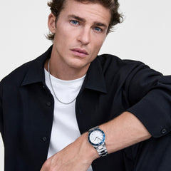 ダークネイビーのシャツと白Tシャツを合わせた男性が、Iconic Paradigma Link Blue Bezel Silverを着用しています。ブルーのベゼルとシルバーブレスレットが手元に爽やかなアクセントを加え、カジュアルなスタイリングに自然になじむデザインです。