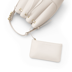 Lewis Bag Crèmeに付属のDaniel Wellingtonロゴ入りポーチのクローズアップ画像です。ドローストリングでバッグ本体と連結されており、ゴールドのハトメやクリーム色エコレザーのなめらかな質感が白い背景に映えています。