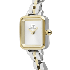 Quadro Mini Arch 3-Link Two Tone Goldの文字盤とケースを斜めからとらえたクローズアップ画像です。ゴールドのベゼルとシルバーのケースが重なる二層構造や、インデックスのないホワイトサンレイダイヤル、ゴールドのリューズの丸みなど、細部の美しさが際立ちます。