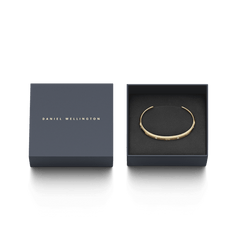 Classic Lumine Braceletのゴールドカフが、ネイビーのブランドボックスに収められたギフトパッケージです。箱の蓋にはDaniel Wellingtonのロゴが箔押しされており、贈り物にぴったりの上品な仕上がりとなっています。